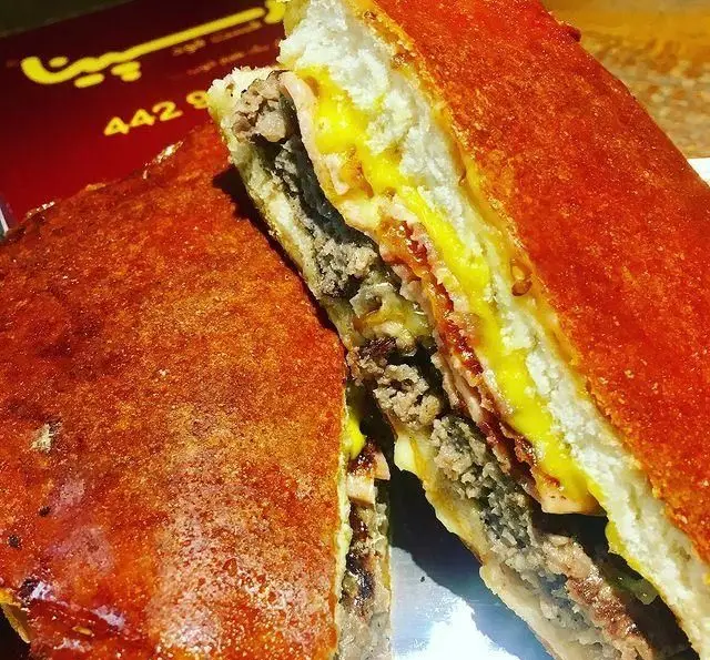 ساندویچ دوبل برگر گوشت و پنیر ذوب شده از فست فود رسپینا، با نان بسیار ترد و طلایی، لذیذ و پرملات.