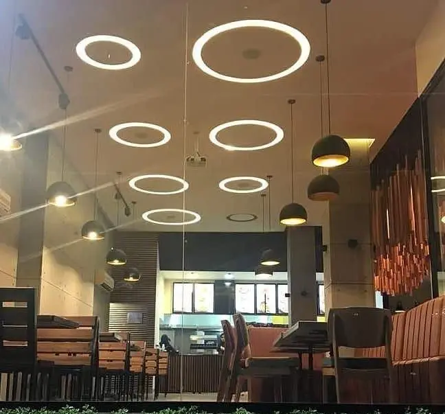 تصویری از داخل رستوران ویانا، محیطی مدرن با چیدمان زیبای میز و صندلی و نورپردازی خلاقانه سقفی و چراغ‌های آویز شیک.