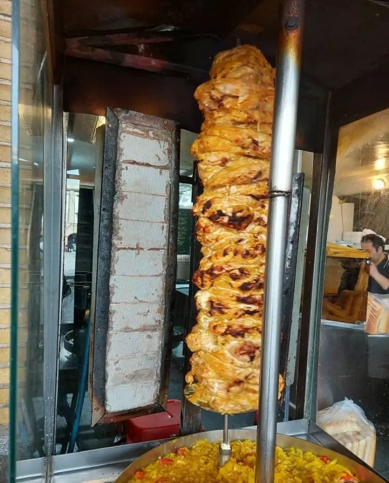 سیخ بزرگ کباب ترکی مرغ آبدار و طلایی، در حال پخت و آماده برای سرو در رستوران فست فود ایران برگر (سرزمین سوخاری) با طعمی دلپذیر.