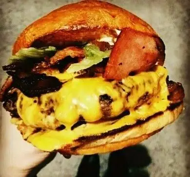 همبرگر دوبل پنیر و بیکن خوشمزه از فست فود هیزم. این ساندویچ با نان برشته، دو پتی گوشت آبدار، پنیر آب شده، بیکن ترد و کاهو آماده شده.