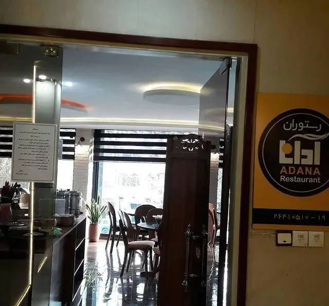 ورودی مدرن رستوران آدانا با تابلوی نام تجاری، نشان‌دهنده فضای داخلی روشن و دلپذیر با میز و صندلی‌های شیک، پنجره‌های بزرگ و پیشخوان.