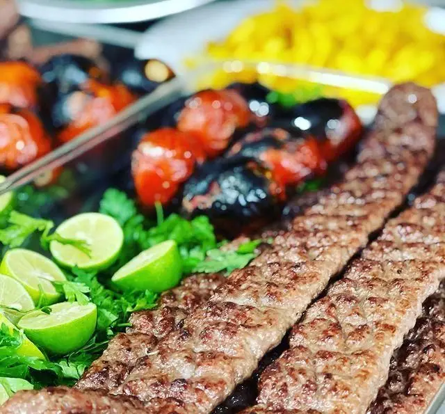 کباب کوبیده داغ رستوران حمید با گوجه کبابی آبدار، سبزی معطر و برش‌های لیموی تازه. لذت غذای اصیل ایرانی.