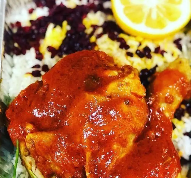 مرغ خوش پخت با سس مخصوص، زرشک پلو مجلسی و برنج زعفرانی، همراه با برش لیموی تازه از رستوران حمید.