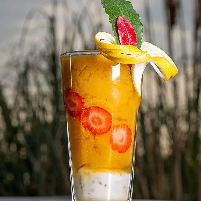 نوشیدنی خنک و لایه‌لایه کافه رستوران لول ۴: اسموتی انبه با توت فرنگی و پودینگ چیا، تزیین شده با پوست موز و برگ.