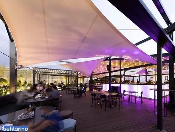 کافه رستوران لول ۴، نمایی از فضای باز دلنشین با سایبان‌های سفید، نورپردازی بنفش و میز و صندلی چوبی در محیطی دنج و مدرن.