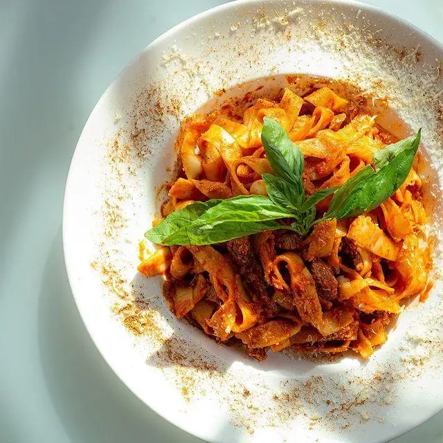 پاستای فتوچینی یا تالیاتله ایتالیایی دلپذیر با سس گوجه‌فرنگی، گوشت و پنیر، مزین به ریحان تازه در کافه رستوران لول ۴.
