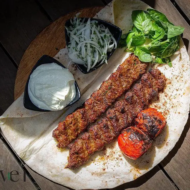 کباب کوبیده لذیذ کافه رستوران لول ۴ با نان لواش، گوجه کبابی، پیاز و سبزی تازه. تجربه‌ای دلنشین از غذای اصیل ایرانی.