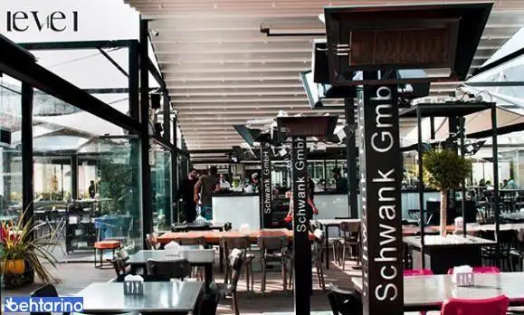 فضای داخلی کافه رستوران لول ۴ با دکوراسیون مدرن و شیک، میز و صندلی‌های متعدد آماده پذیرایی از مشتریان در محیطی بزرگ و دلنشین.