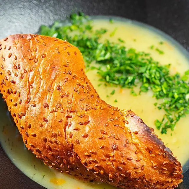 تصویری جذاب از نان کنجدی برشته در کنار سوپ سبزیجات تازه، غذایی لذیذ و مقوی از کافه رستوران لول ۴.