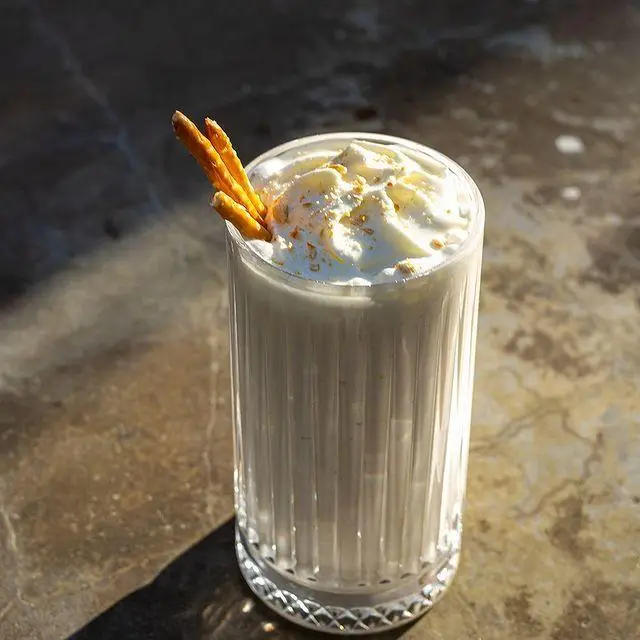 یک میلک شیک خوشمزه و خنک از کافه رستوران لول ۴، با خامه فرم گرفته و چوب شور تزئین شده، تجربه‌ای لذت‌بخش و دلپذیر.