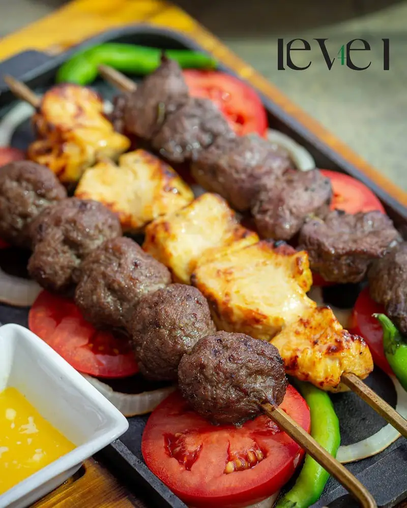 نمای نزدیک از سیخ‌های کباب کوفته‌ای، جوجه کباب و کباب گوشت تکه‌ای تازه و لذیذ سرو شده روی سینی در کافه رستوران لول ۴.