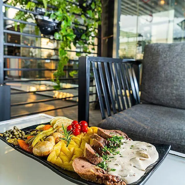 بشقاب غذای لذیذ شامل گوشت اسلایس شده، پوره، سبزیجات تازه و سس خامه‌ای در کافه رستوران لول ۴، انتخابی عالی برای شما.