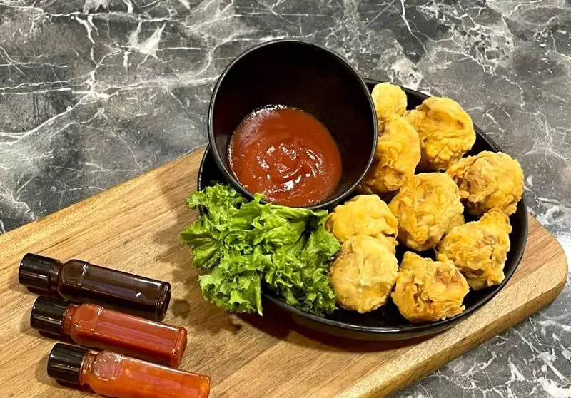 نمایی از پاپ کورن مرغ سوخاری طلایی و ترد Vee با سس کچاپ، کاهو و سه نوع سس دیگر، آماده در رستوران فست فود Vee.