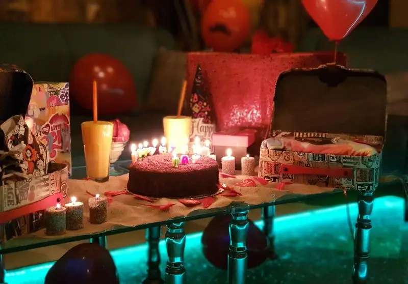 جشن تولد شاد و خاطره‌انگیز در کافه ژیکو: کیک شکلاتی، شمع‌های روشن، هدایا و دکوراسیون رمانتیک و دنج.