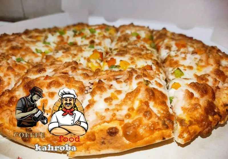 پیتزای داغ و لذیذ با پنیر کش‌دار و فلفل دلمه‌ای تازه، آماده سرو در کافه فست فود کهربا، غذای خوب.