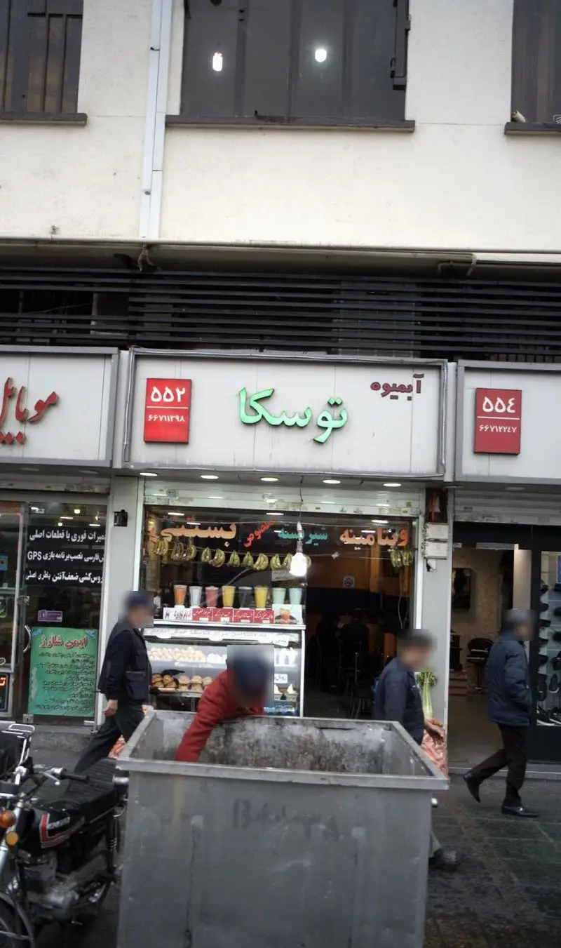 نمای خیابانی از آبمیوه توسکا، فروشگاه محبوب آبمیوه و ویتامینه در تهران با مشتریان و ویترین محصولات تازه و طبیعی.