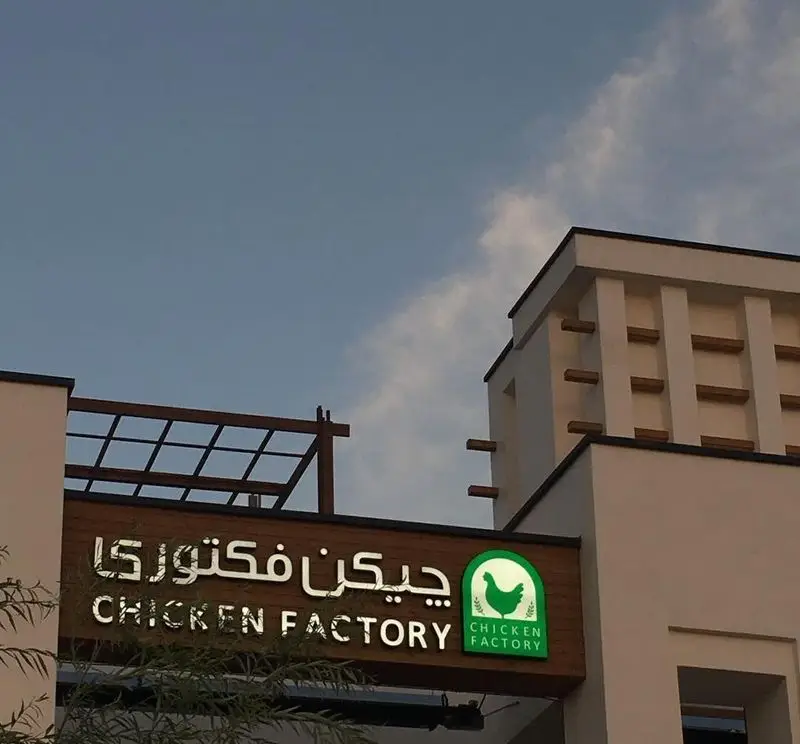تصویری از نمای بیرونی رستوران فست فود چیکن فکتوری در مجتمع بام لند، شامل تابلوی درخشان با نام و لوگوی مرغ، آماده سرو غذاهای لذیذ مرغی.