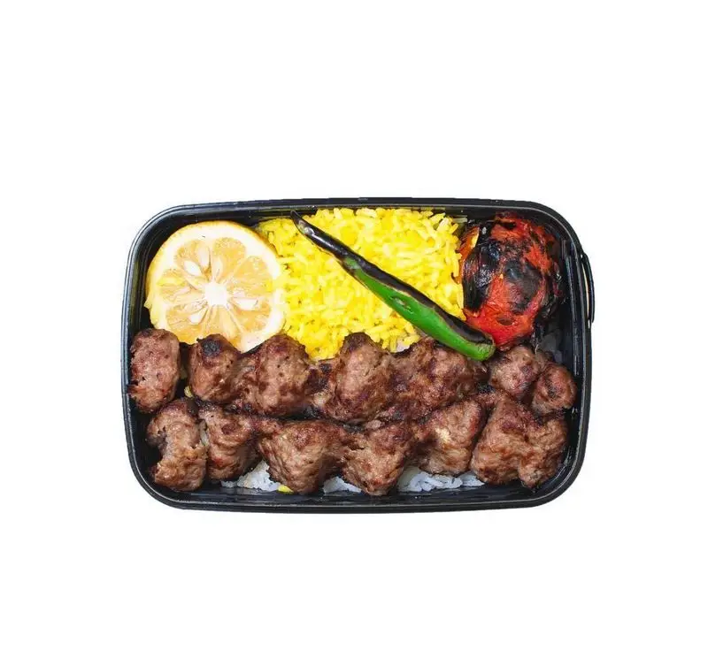 غذای آماده کباب کوبیده لذیذ از روحی اکسپرس شهرک غرب، شامل دو سیخ کباب، برنج زعفرانی، گوجه کبابی، فلفل و برش لیمو تازه.