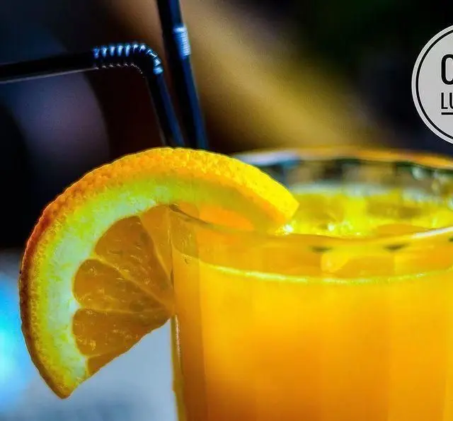 یک لیوان آب پرتقال طبیعی و گوارا با تزئین برش پرتقال، نوشیدنی خنک و انرژی‌بخش مناسب برای مشتریان کافه رستوران لومیر.