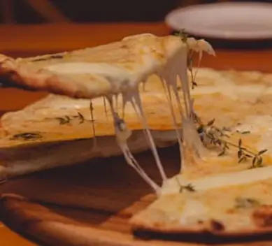 یک برش پیتزای داغ با پنیر کش‌دار و معطر در کافه رستوران لومیر. طعمی بی‌نظیر برای تجربه غذای عالی در محیطی دلپذیر.