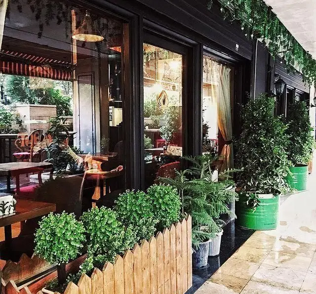 نمای بیرونی کافه رستوران لومیر با پنجره‌های بزرگ، گیاهان سبز و دکوراسیون دلنشین؛ محیطی دنج و ایده‌آل برای اوقات خوش شما.