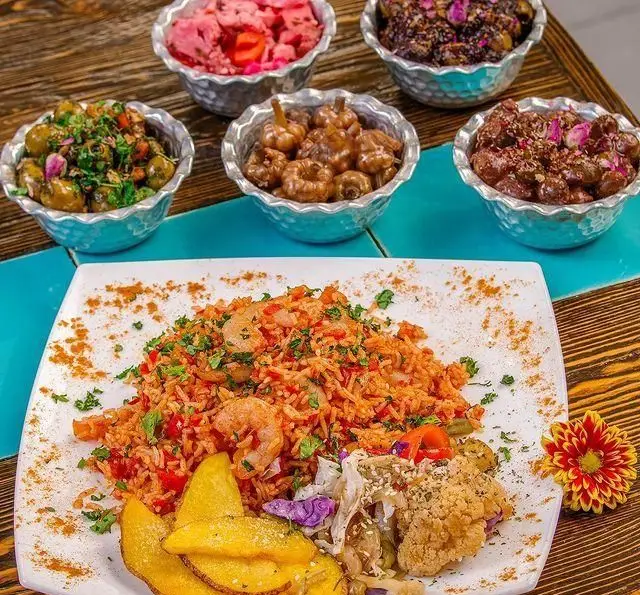 غذای دریایی لذیذ پلو میگو، سیب زمینی و سالاد در رستوران گیلکی بهزاد، همراه با ترشیجات و زیتون پرورده تازه و رنگارنگ.