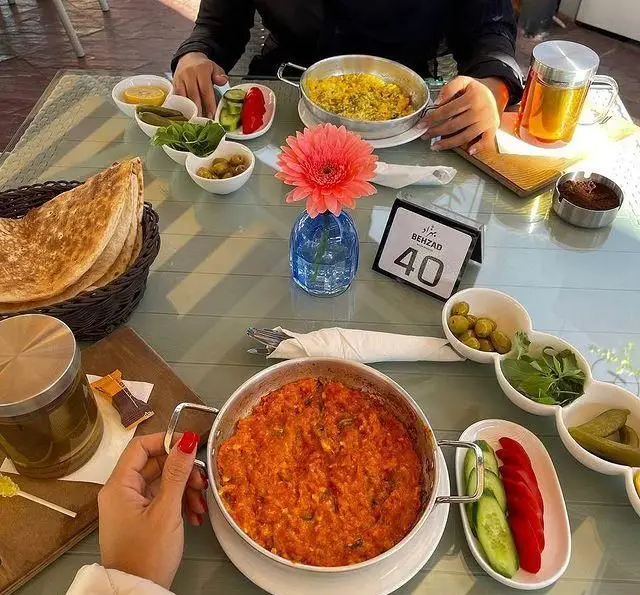 صبحانه سنتی گیلکی در رستوران گیلکی بهزاد. میزی چیده از غذاهای محلی گیلان، نان تازه، املت و مخلفات تازه.