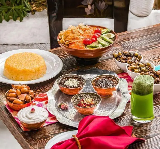 نمایی دلپذیر از میز غذاهای متنوع گیلکی در رستوران گیلکی بهزاد، از پلو و خورش‌های خوش‌طعم تا مخلفات محلی و نوشیدنی خنک.