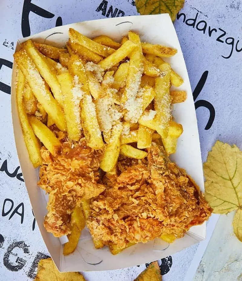 یک سینی غذای فست فود شامل مرغ سوخاری ترد و سیب زمینی سرخ کرده با پنیر پارمزان از برگرلند، آماده برای لذت بردن.