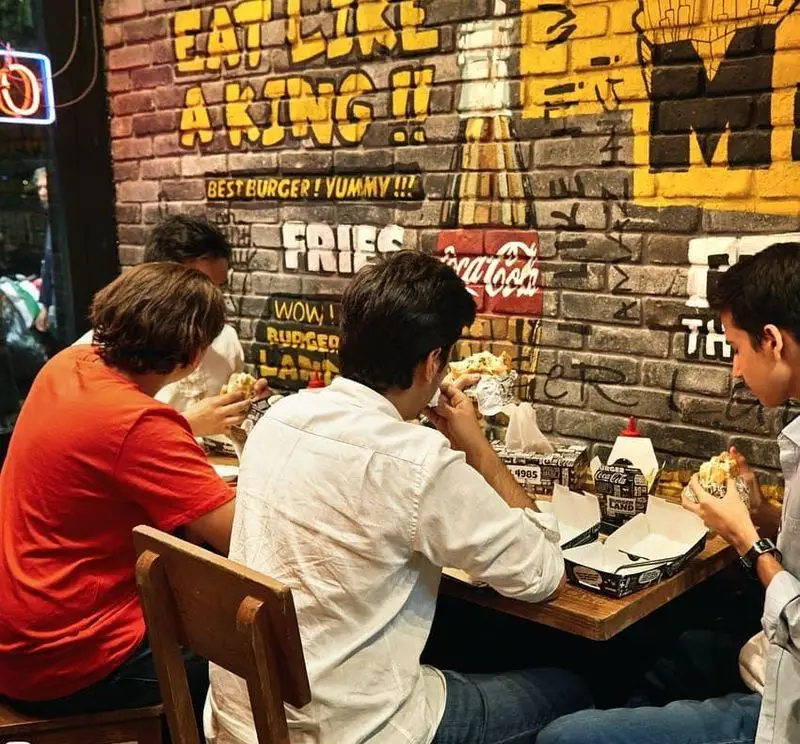 مشتریان در رستوران برگرلند مشغول لذت بردن از برگرهای خوشمزه و فست فودهای باکیفیت. تجربه غذایی عالی در محیطی دوستانه.