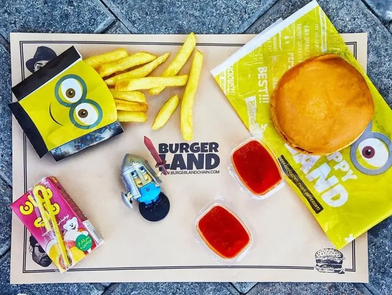 غذای فست فود برگرلند: برگر، سیب‌زمینی سرخ کرده با بسته بندی مینیون، آبمیوه، اسباب‌بازی و سس کچاپ. منوی کودکانه برگرلند.