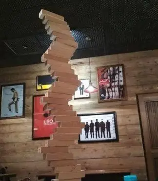 کافه قلیان نیمکت: دکوراسیون داخلی خلاقانه با مجسمه چوبی مارپیچ جنگا، عنصری جذاب در طراحی فضای کافه قلیان مدرن.