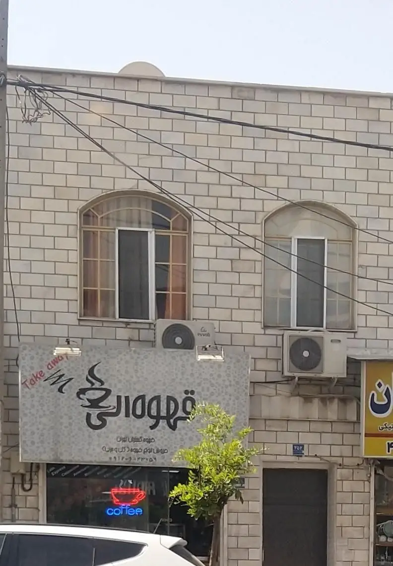 تصویری از نمای ساختمان آجری کافه قهوه الی در گیلان، تابلوی اصلی با لوگوی فنجان قهوه، اطلاعات تماس و نئون "coffee".