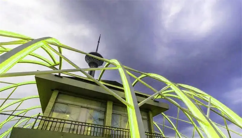 ایوان برج میلاد: نمایی از معماری مدرن رستوران فرنگی ایوان برج میلاد، با خطوط منحنی سبز و گنبد برج میلاد در آسمان تهران.