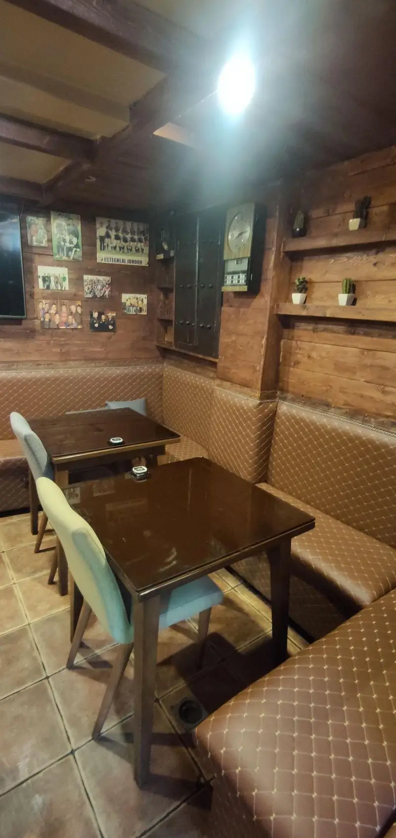 تصویری از فضای داخلی دلنشین کافی شاپ پاییز ۹۸ با دیوارهای چوبی، سقف تیرکوب، نیمکت‌های قهوه‌ای چرمی و میزهای شیشه‌ای براق، مناسب پاتوقی گرم.