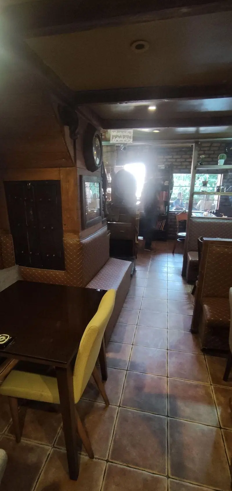 تصویری از فضای داخلی دنج و دلنشین کافی شاپ پاییز ۹۸ با میزهای چوبی، صندلی‌های راحت و نورپردازی گرم، محیطی عالی برای مشتریان.