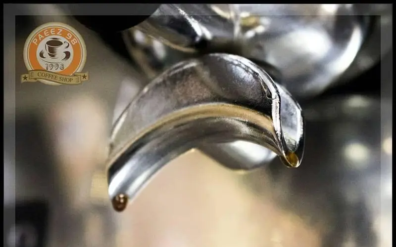 تصویری ماکرو از پرتافیلتر دستگاه اسپرسو کافی شاپ پاییز ۹۸، با دو قطره قهوه تازه و غلیظ. تجربه نوشیدنی‌های خاص در Paeez 98.