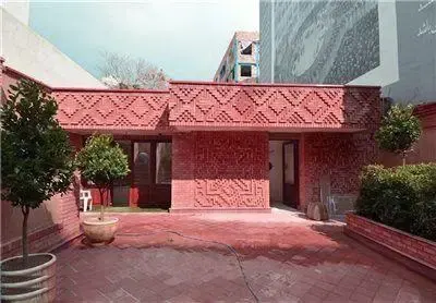 ورودی اصلی خانه موزه استاد عزت الله انتظامی در تهران با دیوارهای آجری قرمز و نقش‌های برجسته هنری، منعکس‌کننده معماری سنتی ایرانی.