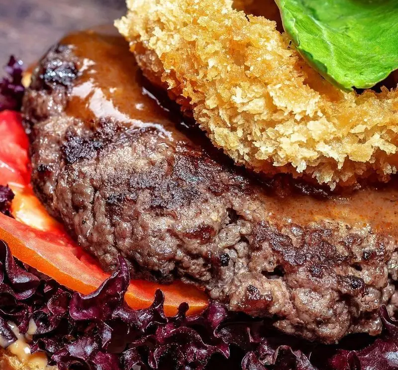 همبرگر دست‌ساز آوافودمارکت آواسنتر با پتی گوشت گریل شده، سس مخصوص، پیاز سوخاری و سبزیجات تازه. لذت طعم در مجتمع تجاری آواسنتر.