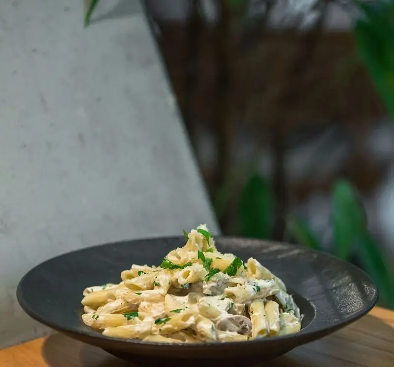 پاستا پنه با سس آلفردو خامه ای و قارچ، تزئین شده با جعفری، از منوی لذیذ آوافودمارکت در مجتمع تجاری آواسنتر.