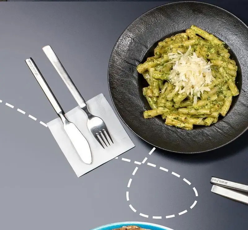 پاستای لذیذ پستو با سس سبز و پنیر در بشقابی شیک، همراه کارد و چنگال. منوی متنوع آوافودمارکت مجتمع تجاری آواسنتر.