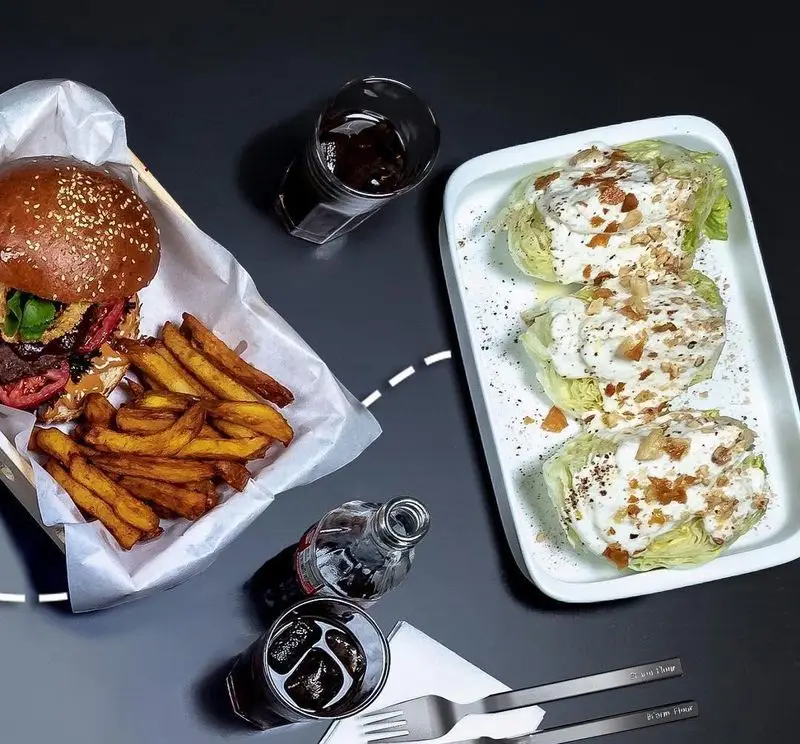 نمایی از میز غذای آوافودمارکت آواسنتر شامل برگر ویژه، سیب‌زمینی طلایی، سالاد خوش‌طعم و نوشیدنی‌های گوارا