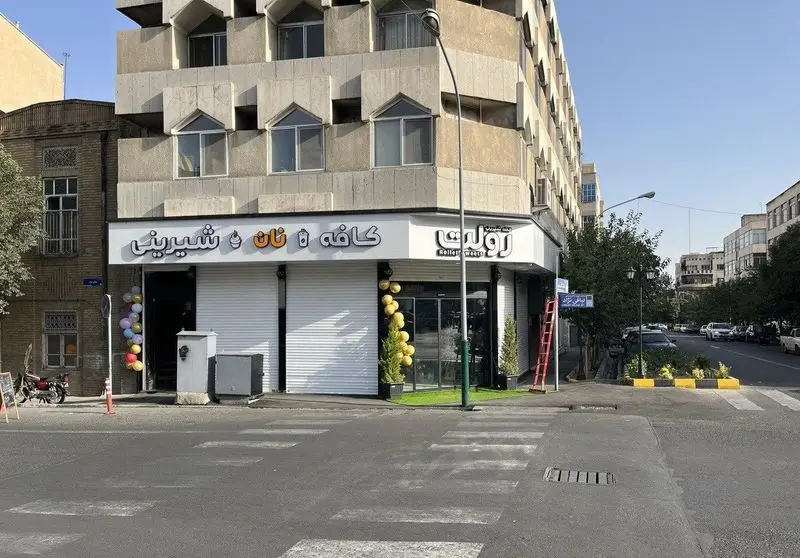 نمای بیرونی کافه قنادی رولت، یک شیرینی فروشی و کافی شاپ شیک در گوشه خیابان، با دکوراسیون بادکنکی رنگارنگ.