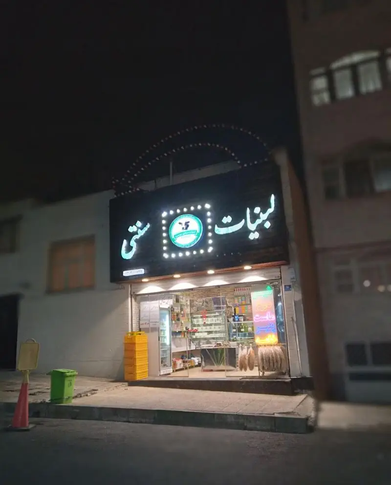 نمای شب از فروشگاه لبنیات سنتی برادران با تابلوی روشن، ارائه دهنده انواع محصولات لبنی محلی و سنتی در شهر.
