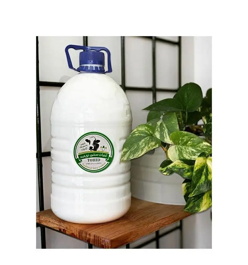 بطری بزرگ دوغ سنتی توحید، محصولی تازه و باکیفیت از لبنیات سنتی برادران، قرار گرفته بر روی قفسه چوبی.