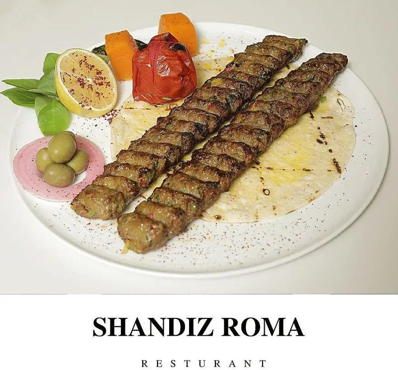 دو سیخ کباب کوبیده آبدار رستوران شاندیز روما روی نان داغ، همراه با گوجه کبابی، لیمو، زیتون و سبزی تازه. غذای لذیذ ایرانی.