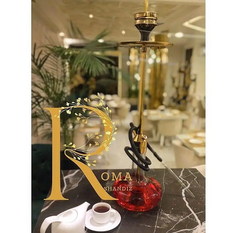 لوگو 'R' شاندیز روما روی میز مرمر، در کنار قلیان طلایی لوکس و چای. رستوران و کافه شاندیز روما، فضایی دلنشین و خاص.