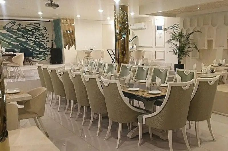 فضای داخلی رستوران شاندیز روما با دکوراسیون مدرن و شیک، میزهای مجلل، صندلی‌های راحتی و دیوارنگاره هنری زیبا، محیطی لوکس و دلپذیر برای صرف غذا.