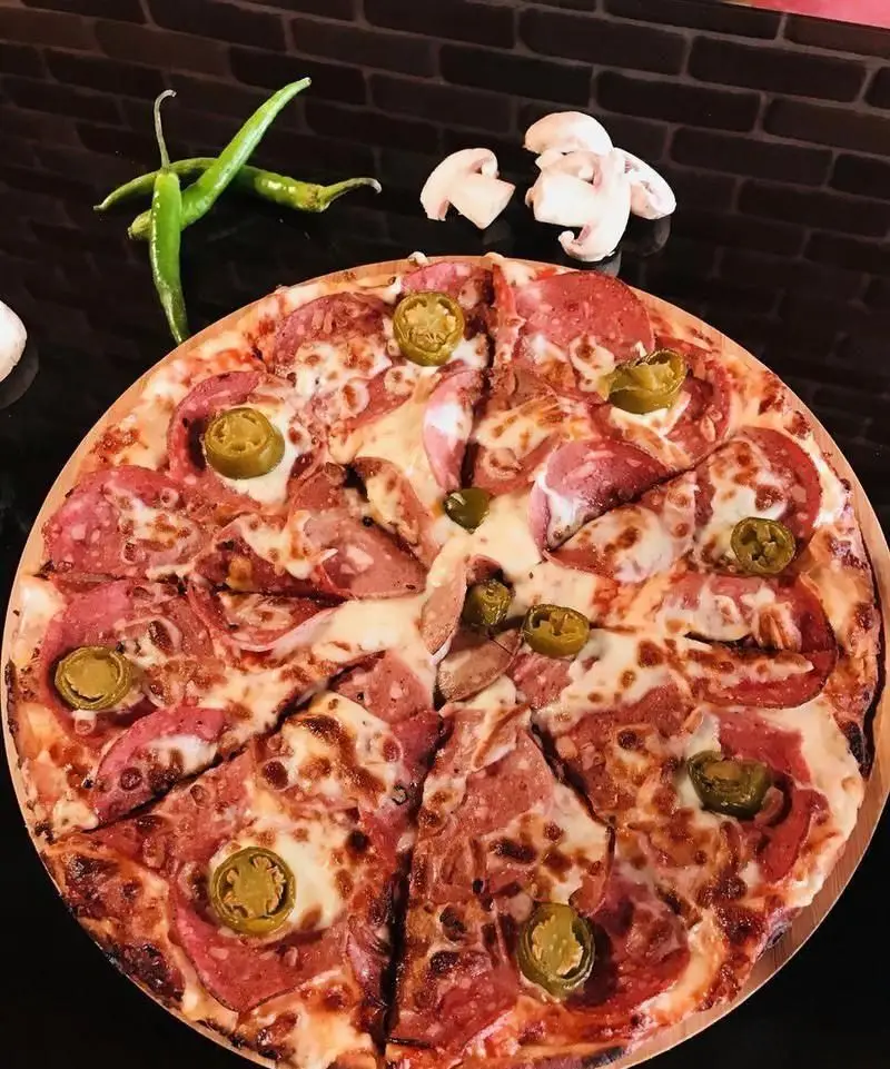 پیتزا پپرونی و سالامی خوشمزه کافه رستوران فوژر با پنیر فراوان، فلفل هالوپینو، قارچ و فلفل سبز تازه برای یک تجربه ایتالیایی.