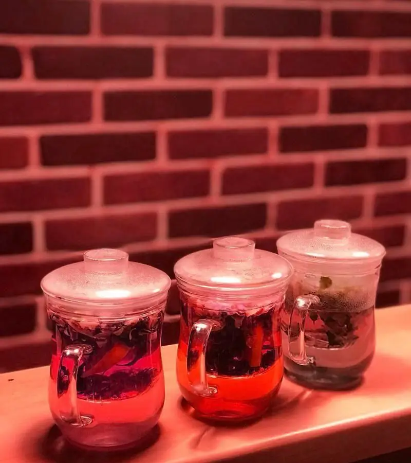 دمنوش‌های لذیذ و رنگارنگ در لیوان‌های شیشه‌ای شفاف کافه رستوران فوژر، در محیطی دنج با دیوار آجری، تجربه‌ای لذت‌بخش.